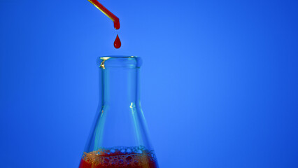 A drop of blood. Pipette. On a blue background. Medical flask with red liquid. Flask with blood. Dripping red liquid. A drop of red. Tests, blood group.
