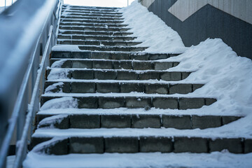 Wintery stone staircase covered with snow and ice layer outdoor. Slippery steps in winter season...