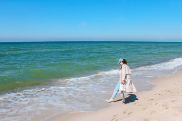 a girl walks along the shore of the blue sea on the sandy shore. summer mood