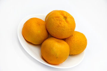 Juicy tangerines on a plate on a white background. Juicy citrus fruits. Slices of tangerines.