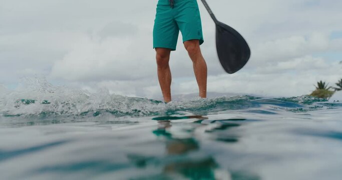 Close up of man stand up paddle boarding on tropical beach vacation