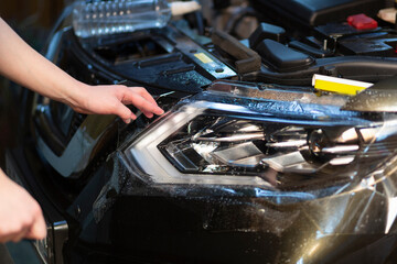 Installation of a protective film on the headlights of the car.Car body protection.