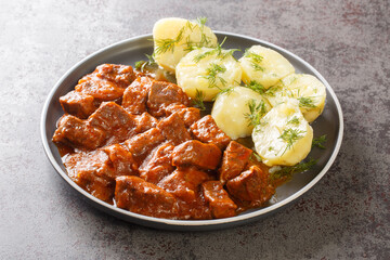 Viennese beef goulash with thick sauce served with boiled potatoes close-up on a plate on the...