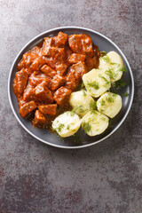 Vienna Goulash or Wiener Saftgulasch served with boiled potatoes closeup on the plate on the table. Vertical top view from above