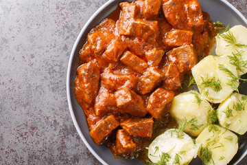 Austrian beef goulash in a thick rich sauce with boiled potatoes close-up in a plate on the table....