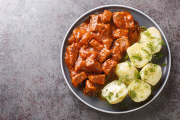 Viennese beef goulash with thick sauce served with boiled potatoes close-up on a plate on the table. horizontal top view from above