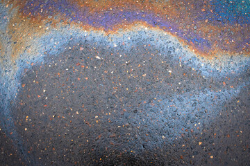 Oil stain on the asphalt, rainbow-shaped colored gasoline stains on an asphalt road