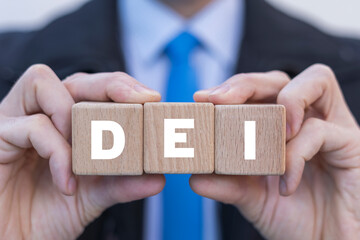 Man holding wooden cubes with abbreviation: DEI. Concept of DEI Diversity Equality Inclusion. Multiracial Multicultural Community Belonging Human Rights.