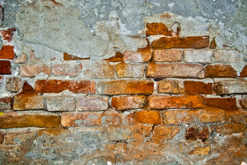 Wall of bricks with fallen plaster in a city