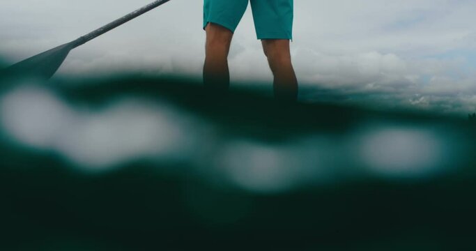 Close up of man stand up paddle boarding on tropical beach vacation