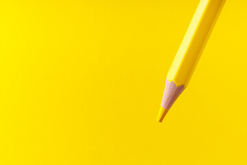 Fototapeta premium Colored pencil close-up with selective focus on the stylus and a blurred yellow background. Copy space