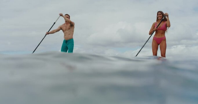Couple stand up paddle boarding on tropical beach vacation, travel vacation lifestyle