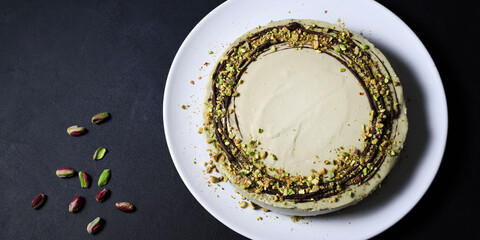 Cheesecake al pistacchio, torta di mousse con decorazione di pistacchio tritato su un piatto bianco.