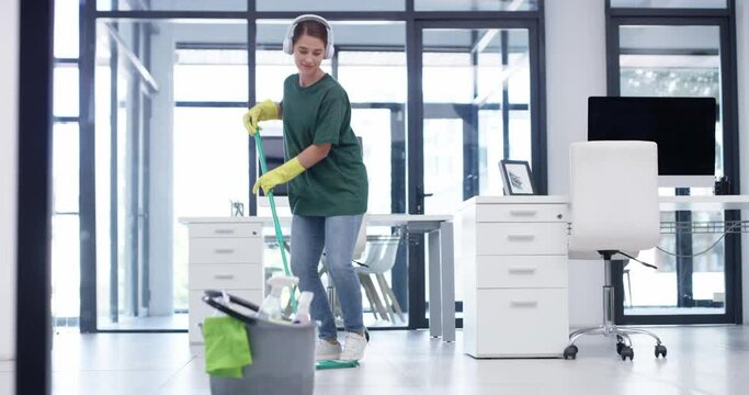 Cleaner, listening to music and mopping office floor while dancing and having fun with headphones while working for cleaning service. Woman with mop to clean for janitor or maid work at business