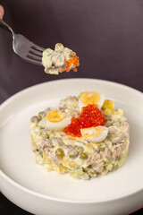 A man holds a plate with a Russian winter salad