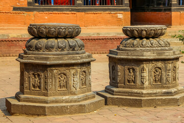 Two stone buddhist altars with carved gods and vajras stands in courtyard (bahal) of Ratnakar...