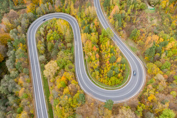 Aerial view on curvy road amid colourful autumn forest in Bieszczady, Poland