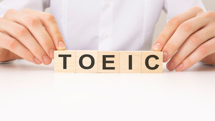 the hands turns the wooden cube and word TOEIC