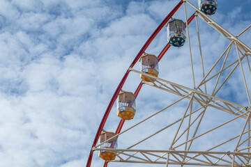 Colorful ferris wheel cabins view in central park, Kharkiv city. Amusement attraction on cloudy sky...