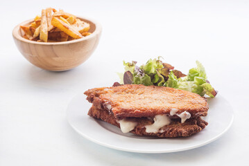 steak filled cheese and ham (san jacobo, librito) with salad and potatoes chips
