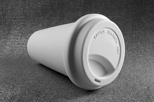 Close-up of Take out Coffee Cup on it's Side with Caution Contents Hot Warning on Lid, Studio Shot