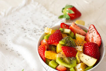 Bowl of healthy fresh fruit salad on white background. Top view