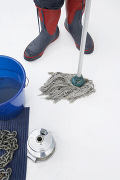 Close-up of Person Wearing Rubber Boots and Mopping Boat Deck
