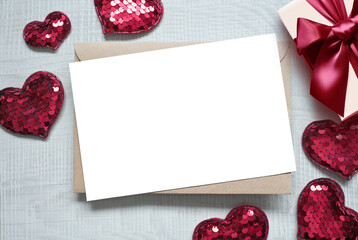 Blank white greeting card with brown envelop and hearts on marble table. Mockup valentines day concept.