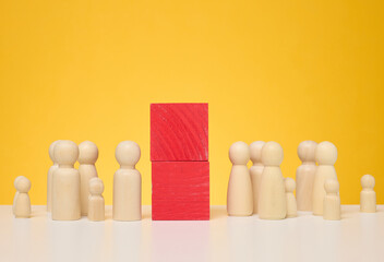 Two crowds of wooden figurines are separated by red blocks. The concept of misunderstanding and separation