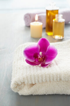 Orchid on a towel, candle, bottles of oil, wellness