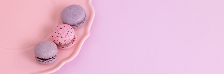 Banner purple and pink macaron cookies lie on a plate