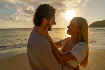 Newly engaged couple enjoying a romantic embrace during the golden hour on an empty sandy beach