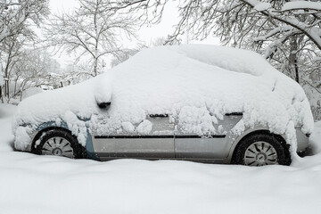 The car in the parking lot is completely covered with snow. Problems after heavy snowfall.