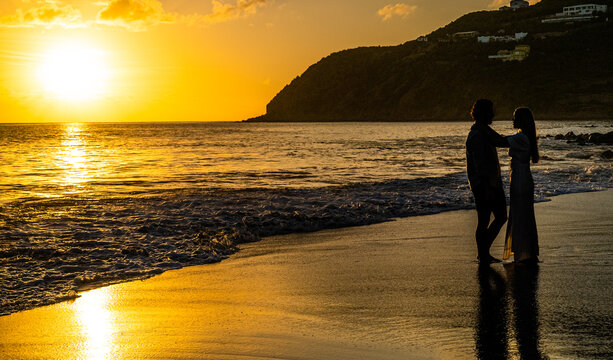 Young couple looking at each other on an empty remote island beach during a picturesque sunset