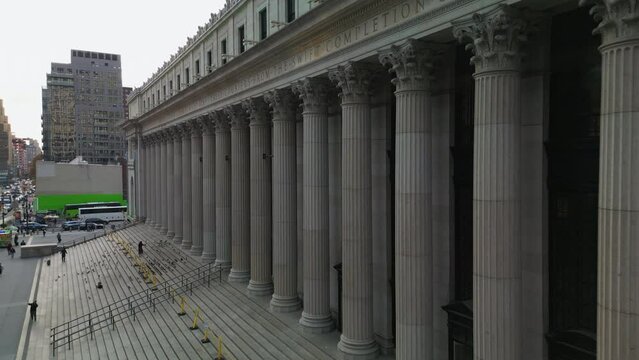 Flight shot around Moynihan Train Hall. Historic building of former main post office building with wide stairs and row of columns. New York City, USA