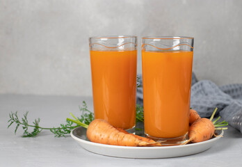 Fresh carrot juice in two glasses on light gray background. Concept of healthy eating and dieting