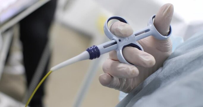Close-up. The doctor holds an endoscopic biopsy clamp in his gloved hand. The surgeon presses and releases the piston while taking the material for examination with an endoscopic biopsy clamp.