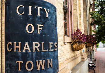 Sign of the City of Charles Town with flowers and bench in West Virginia (WV), USA.