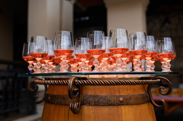 Close view of arranged goblets with cognac beverages, which placed on wooden barrel during wedding celebration