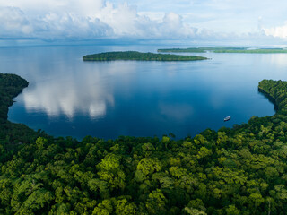 Lush jungle on a remote tropical island is fringed by a coral reef in the Solomon Islands. This...