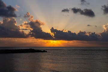 Naklejka na ściany i meble rayons de soleil au travers des nuages lors d'un lever de soleil en bord de mer