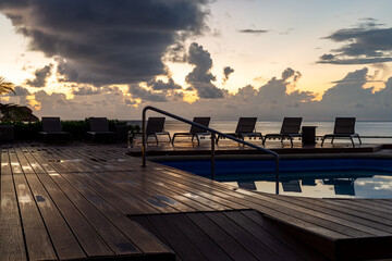 chaises longues en rangées sur un plancher en latte de bois avec vue sur la mer lors d'un lever de soleil