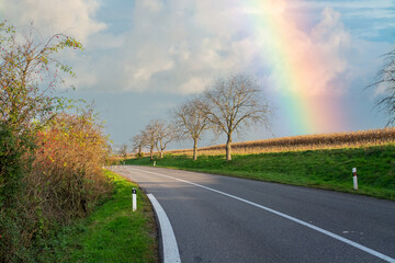 Rainbow. Empty road in the countryside. dry asphalt. Good weather - 555759912