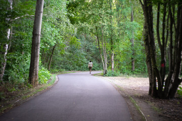 Fototapeta premium The forest road. Lonely pedestrian walking into the distance. Art lens. Swirl bokeh. Focus on the center.