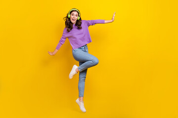 Fototapeta na wymiar Full body portrait of active satisfied lady jumping enjoy new playlist isolated on yellow color background