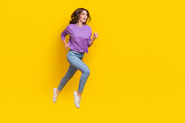 Fototapeta na wymiar Full body profile portrait of cheerful overjoyed lady jumping rush hurry empty space isolated on yellow color background