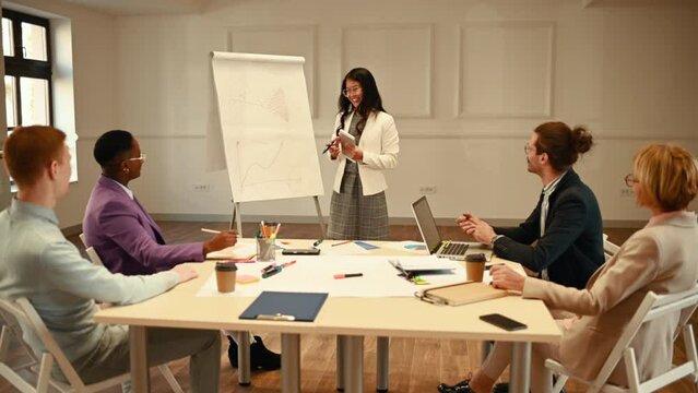 Asian woman holding a meeting and point on a charts on a flipchart board