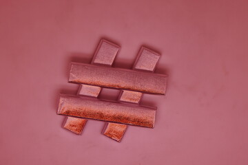 Hash tag number sign made of sweets in a silver wrapper on a light background. Changed color scheme.