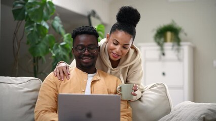 Diverse couple using laptop together at home - Powered by Adobe