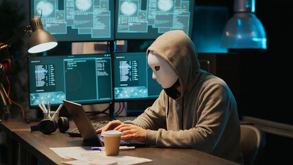 IT thief programmer with mask hacking database servers, hacker with hood on hacking computer system...